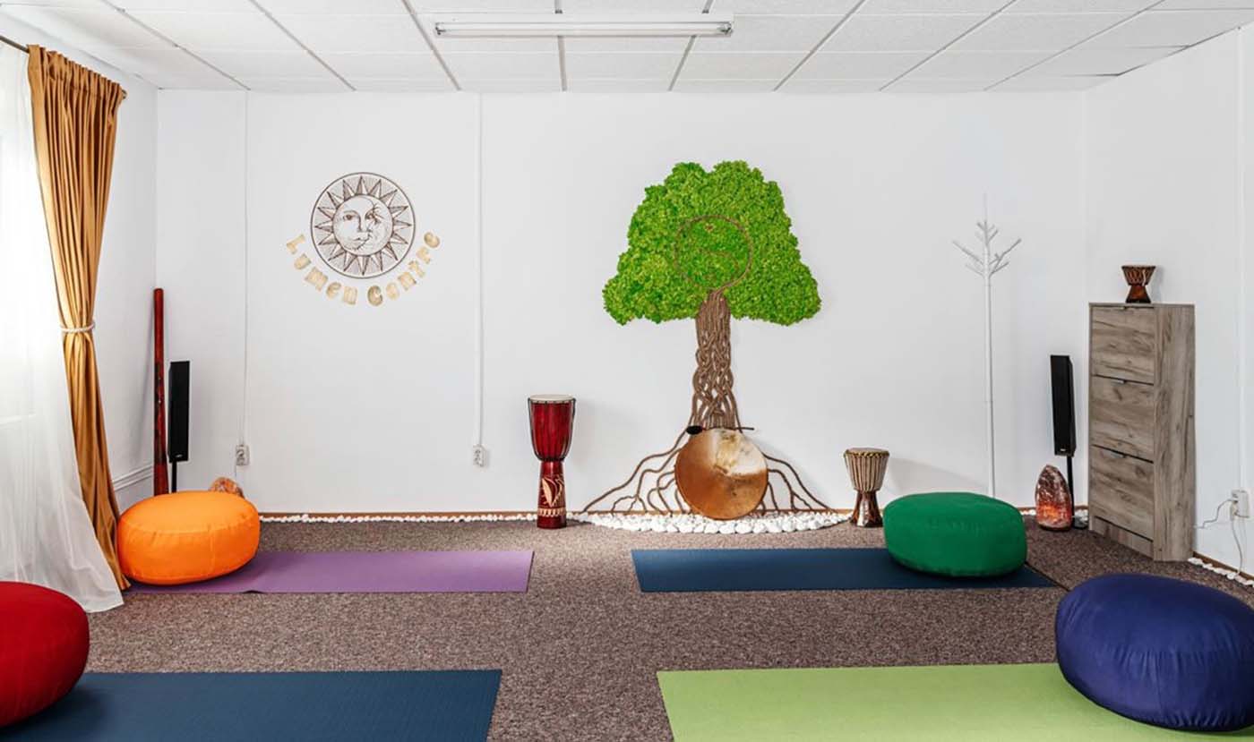 O cameră cu covorașe de yoga și un copac pe perete.