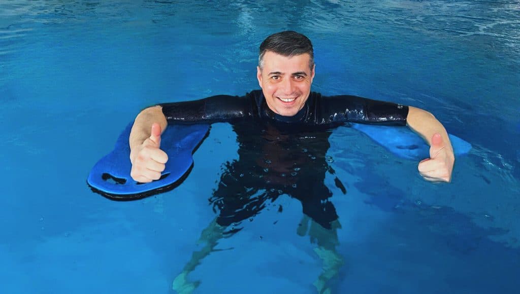 Un bărbat într-o piscină dând degetul mare în sus, demonstrându-și aprobarea.